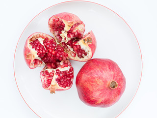 The ripe pomegranate fruit on a white porcelain plate