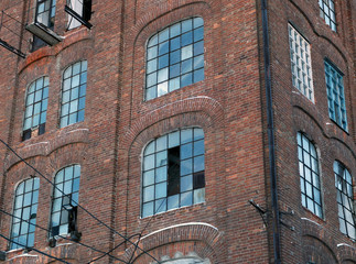 The red brick wall of the old factory with broken windows 
