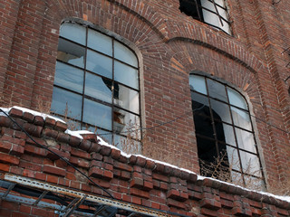 The red brick wall of the old factory with two broken windows 