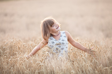 Fototapeta na wymiar Emotional child on wheat field at sunset,pastel