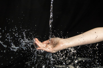 water throwing to a young girl in hands and face with black background
