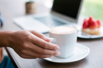 Woman working at home office hand holding coffee cup close up