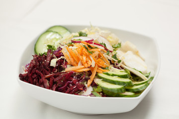 Mixed vegetable salad in a white bowl on white background