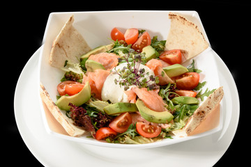 green salad with salmon and tomatoes on plate..