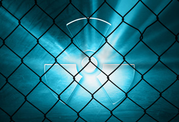 Conceptual shiny glass effect radiation symbol illustration with wire fence background.