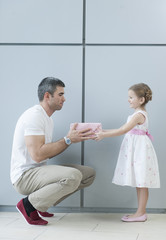 Young girl handing present to her father