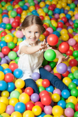 Obraz na płótnie Canvas Young girl in ball pit throwing colored balls