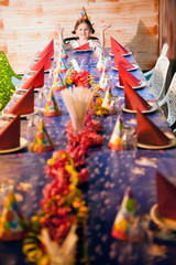 Happy young girl at her dinner party table wearing party hat