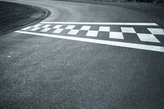 Sunny finish and start line pattern on the winding asphalt race road. © robsonphoto