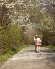 Mother hugging young girl in distance in a park