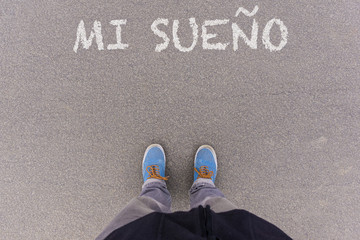 Mi sueno, Spanish text for My Dream text on asphalt ground, feet and shoes on floor