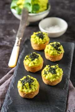 Avocado tartlets made from fresh sliced avocado from above. Dark background. Snack to beer.