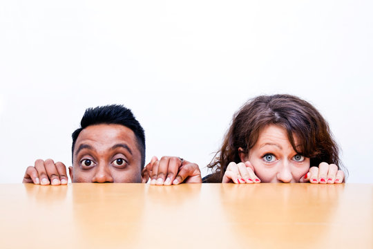 Work Colleagues Peeking Over Edge Of Table