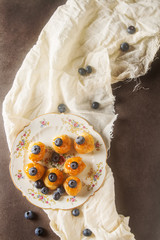 French traditional dessert. Profiteroles with blueberry and apricot jam. Dark background. Light cloth. Top view.