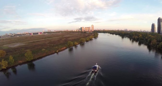 Aerial shots of pleasure boat on the Moskva River at Strogino district of Moscow, Russia. Boat navigate on the Moscow river. Sunrise sunset. Alie parusa buildings
