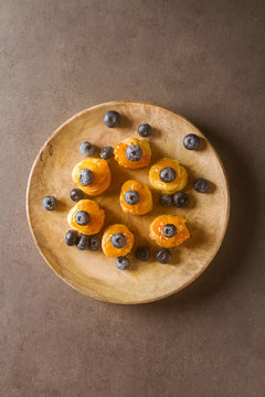 French traditional dessert. Profiteroles with blueberry and apricot jam. Dark background.  Top view.