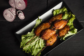 Tasty grilled chicken wings. Dark background. Fast food. Dish. Top view