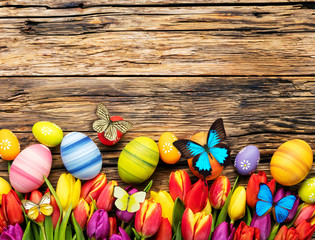 Easter eggs with tulips and butterfly on wooden board