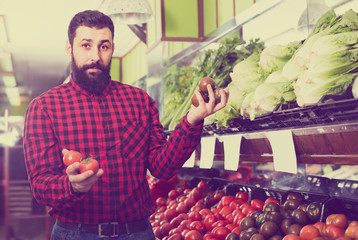 Happy man seller offering tomatoes in shop