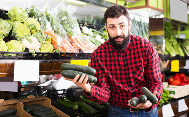 Shop assistant demonstrating zucchinis