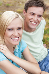 Naklejka premium Portrait of smiling young woman with man relaxing in park
