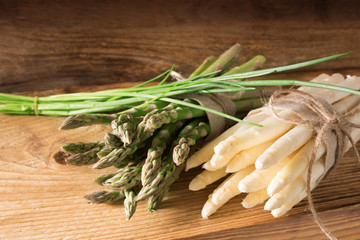 Bunch of asparagus with chives on wood