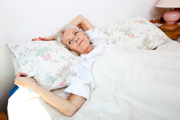 Fototapeta na wymiar High angle view of senior woman looking away while lying in bed at home