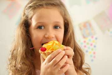 Cute little girl eating tasty cake, close up view