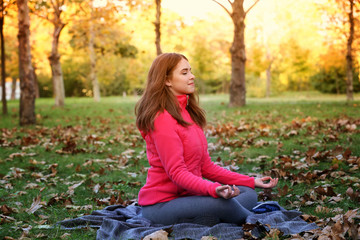 Young beautiful woman doing yoga in autumn park