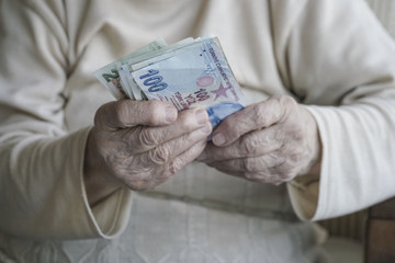 Closeup of wrinkled hands holding turkish lira banknotes