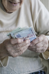 Closeup of wrinkled hands holding turkish lira banknotes