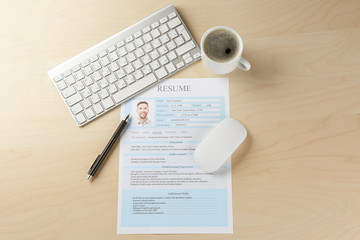Completed CV, keyboard and cup of coffee on wooden table