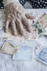 Closeup of wrinkled hand counting turkish lira banknotes
