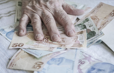 Closeup of wrinkled hand on turkish lira banknotes