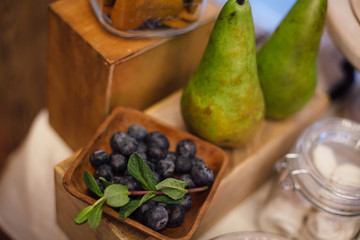 Candy-bar with blueberry,pears and greenery on wooden tray. Sweet bar in area of wedding party.Focus on blueberry