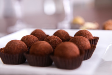 Delicious chocolate truffles on plate closeup