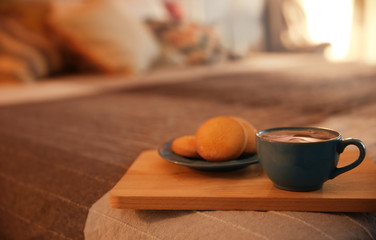 Cookies and cup of hot drink on cozy double bed