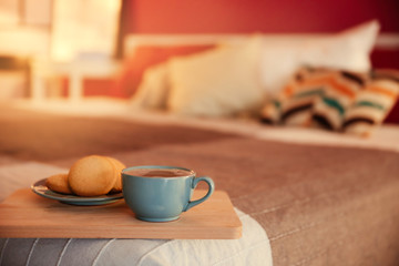 Fototapeta na wymiar Cookies and cup of hot drink on cozy double bed