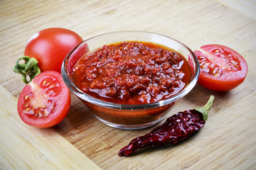 Tomato chutney in a glass bowl on a wooden background