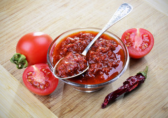 Tomato chutney in a glass bowl on a wooden background