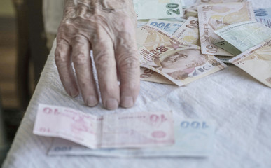 Closeup of wrinkled hand counting turkish lira banknotes