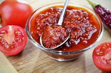 Tomato chutney in a glass bowl on a wooden background