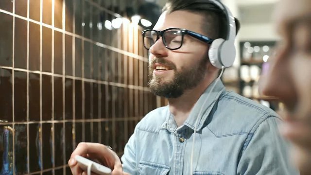 Man enjoying listening music on headphones in the cafe, steadycam shot
