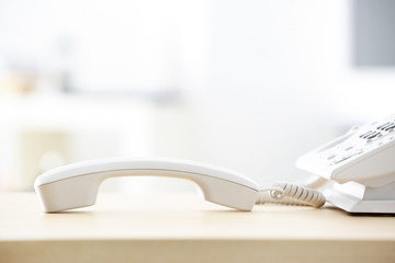 Telephone with picked up receiver on wooden table in office