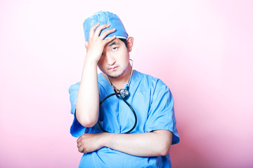 Young  Asian surgeon wearing scrubs and looking stressed