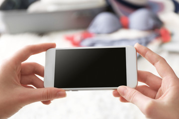 Hands of young woman with mobile phone on blurred background. Travel applications concept