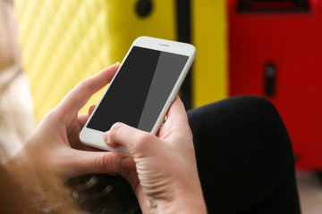 Hands of young woman with mobile phone on blurred background. Travel applications concept