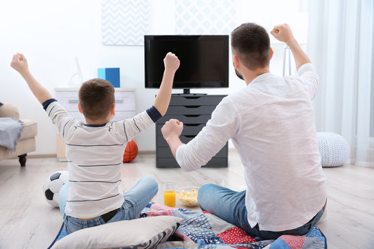 Father And Son Watching Football On TV At Home