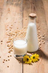Soy milk or soya milk and soy beans on wooden table.