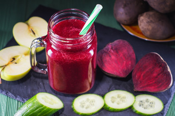 Beetroot smoothie in a mason jar with a straw and ingredients on a wooden background. Fresh beet juice, detox. Organic antioxidant smoothies made of beet, apple, cucumber. Healthy vegan raw food.
